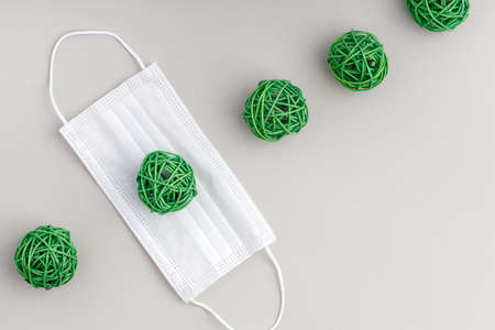 a row of green wicker balloons and a white medical mask. the concept of illness and protection from...
