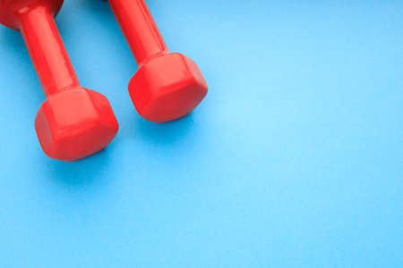 parts of two red dumbbells close-up on a blue background. two red dumbbellsの写真素材
