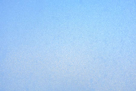 the surface of the frozen glass of blue color, a solid background of hoarfrost in the winter