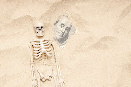 in the dry sand a human skeleton and a hundred dollars. drought and famine, money and sandの写真素材