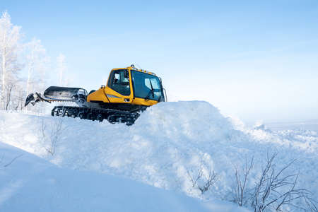 yellow tractor for leveling snow on the ski slope. tractor creates a snow trackの写真素材
