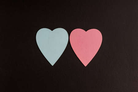 two blue red heart symbols on a black background. wooden hearts