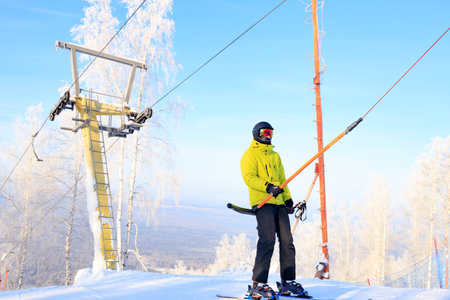 a man in a yellow jacket climbing on a cable car. winter day active timeの写真素材