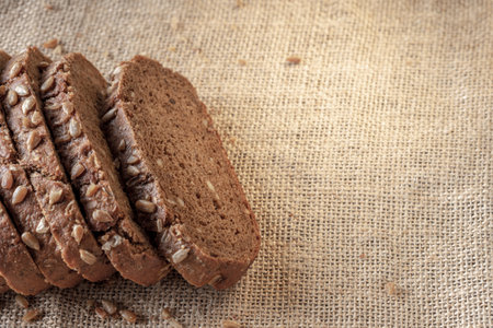 pieces of black bread on burlap, a lot of free space on the right. healthy whole grain bread on...