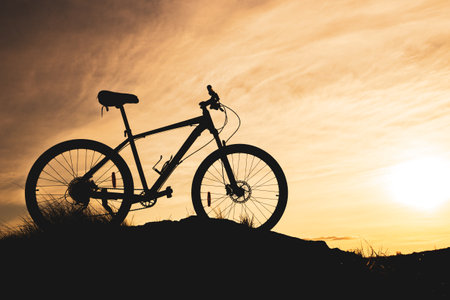 blurry clouds during sunset and a bicycle silhouette in the foreground. bike without people in the...