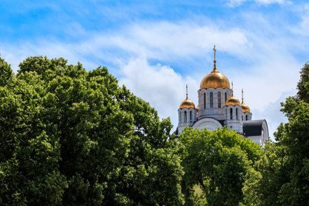 the temple is visible from behind the green trees on a summer day. Orthodox church in the park