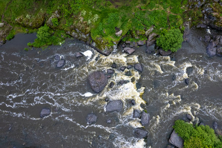 photo from a drone on a part of a mountain river, grass and stones along the banks. swift flow of...