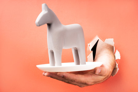 a hand breaks through the paper with a plate on a plate a gray horse. Trojan horse, served as a treatの写真素材