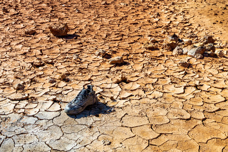 lost shoe on the ground with cracks. found at the bottom of a dry pondの写真素材