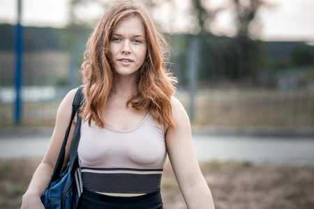 a girl with tousled red hair goes to fitness. outdoor sports on a summer eveningの写真素材