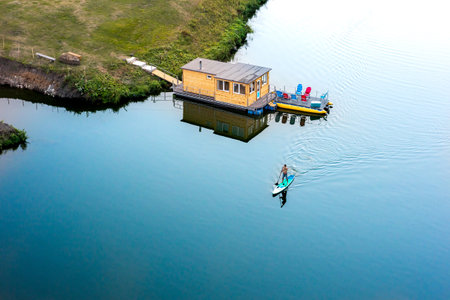 a boat floating on the river, a man rowing on it with an oar on a calm river. the mirror surface of the river and active recreation.の写真素材