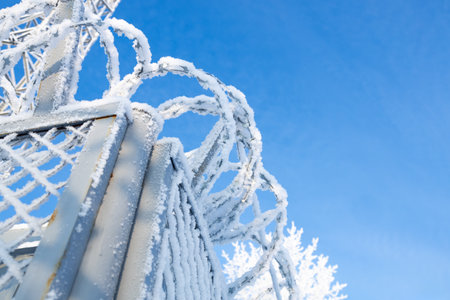the barbed wire on the fence is covered with frost. snow and frost on the fencing fence