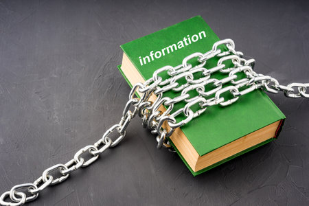 the green book has information written on it, information forbidden to everyone. chains on the bookの写真素材