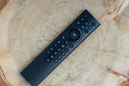 the TV remote is located on a wooden stump. stump texture and plastic remote control. watch TV on a tree stumpの写真素材