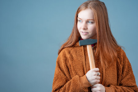 a young woman holds a hammer with both hands and thinks what to do next. thinking about work