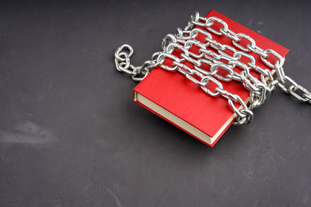 the red book is wrapped with a steel chain on a gray background. the book is bannedの写真素材