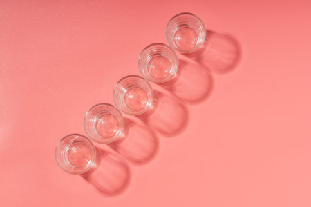 a row of five glasses and their shadows on the surface. top view of empty glasses.