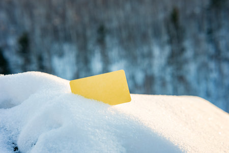 the yellow card is empty without text in the snow. snow and a sign outside in natureの写真素材