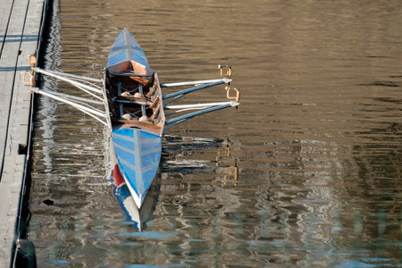 the sports kayak at the pier is on the water. an empty rowing sports boat