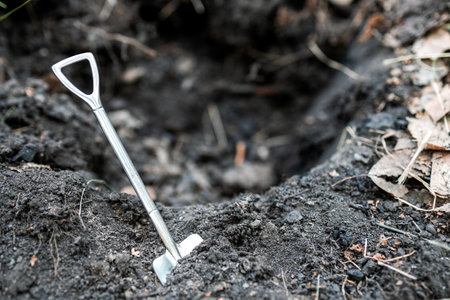 the shovel is near the dug hole, the shallow depth of field background is blurred. metal shovel...