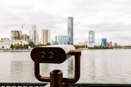 A view of a city from a metal viewing device. The city is in the background and the water is in the foregroundの写真素材