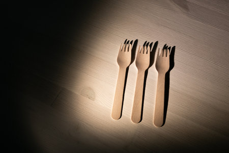 Three forks are on a table, with one fork pointing to the other two. The forks are made of wood and...