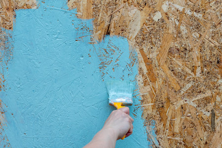 A person is painting a wall with a blue color. The wall is made of wood and has a blue paint on itの写真素材