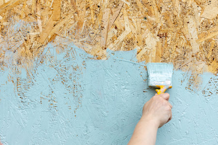a brush is used to paint a chipboard osb. protecting the plate with paintの写真素材