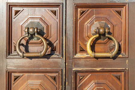 Two doors with brass handles and a wooden frame. The handles are different sizes and shapes. The...