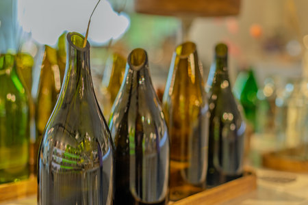 A row of green and black wine bottles sit on a wooden tray. The bottles are all different sizes and shapes, but they all have a similar design. Scene is one of sophistication and eleganceの写真素材