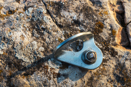 A metal hook is sitting on a rock. The hook is attached to a rope and is used for climbingの写真素材