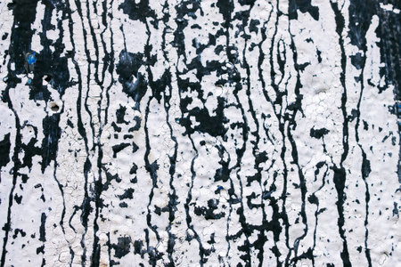 The image is of a wall with black and white splatters of paint. The wall appears to be old and worn, with the paint peeling off in some areas. The splatters of paint create a sense of chaosの写真素材