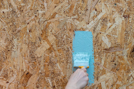 A person is painting a wall with a brush. The wall has a blue paint on itの写真素材