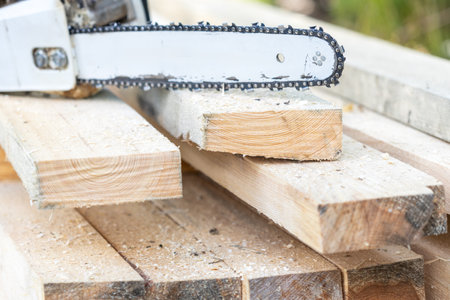The tool for sawing wood is an out-of-focus chainsaw. freshly sawn boards and sawdustの写真素材