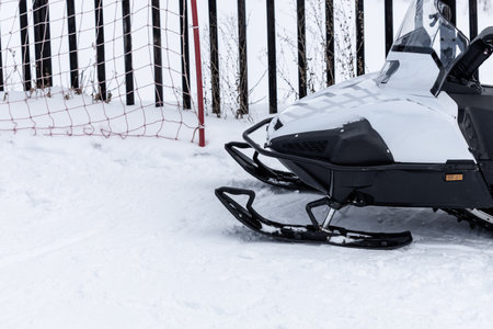 A snowmobile is parked on a snow covered ground. The snowmobile is black and whiteの写真素材
