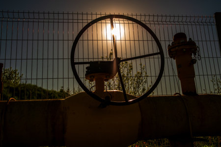 A wheel is on top of a pipe. The wheel is black and the pipe is yellow. The sun is shining on the wheelの写真素材