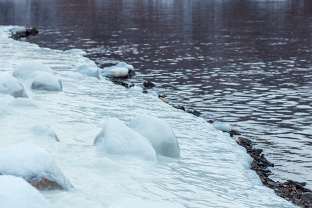 A body of water with ice on the shore. The water is calm and the ice is floating on topの写真素材