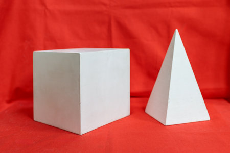 Two white shapes, one square and one triangular, are on a red background. The shapes are made of white material and are placed next to each other. Concept of balance and harmonyの写真素材