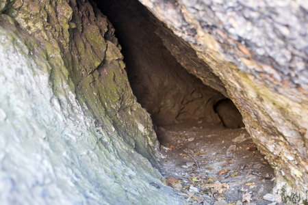 A small cave with a hole in the wall. The cave is dark and has a damp, musty smellの写真素材