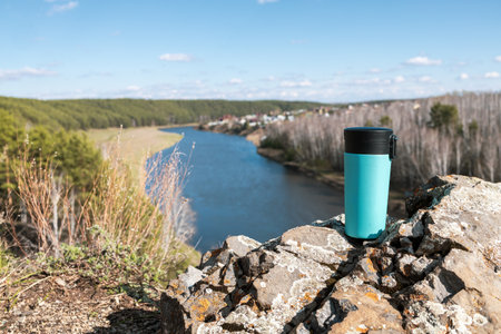 landscape from the height of a mountain, river and forest in the background. thermocup in the foregroundの写真素材