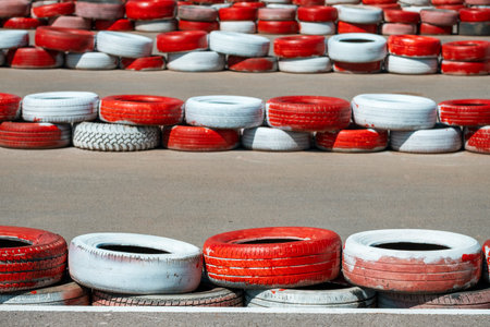 A pile of red and white tires on a road. The tires are stacked in a row and are of different sizesの写真素材