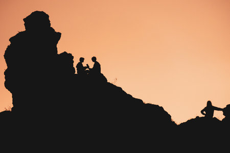 The silhouette of a couple in love against the sunset is sitting opposite each other. The background...