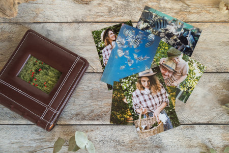 Printed photos and photo album on wooden board. Top view.の写真素材