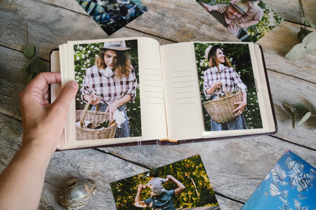 Woman browsing picture album with printed photos.