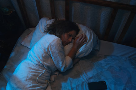 Insomnia. Sleeping troubles. Woman lying awake in bed at night.の写真素材