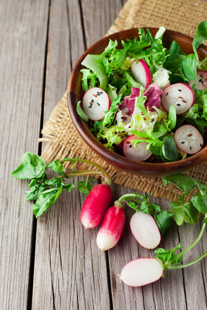 Fresh spring salad with radishes on old wooden background, selective focusの写真素材