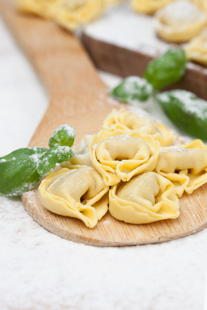 Homemade raw Italian tortellini and basil leaves on a tableの写真素材