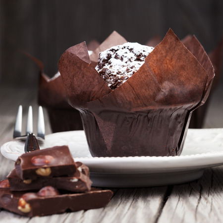 Homemade chocolate muffins with powder sugar on dark wooden backgroundの写真素材