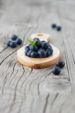 Juicy fresh blueberries in a plate on old wooden background, selective focusの写真素材