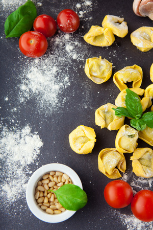 Homemade raw Italian tortellini and basil leaves on a black background, top viewの写真素材